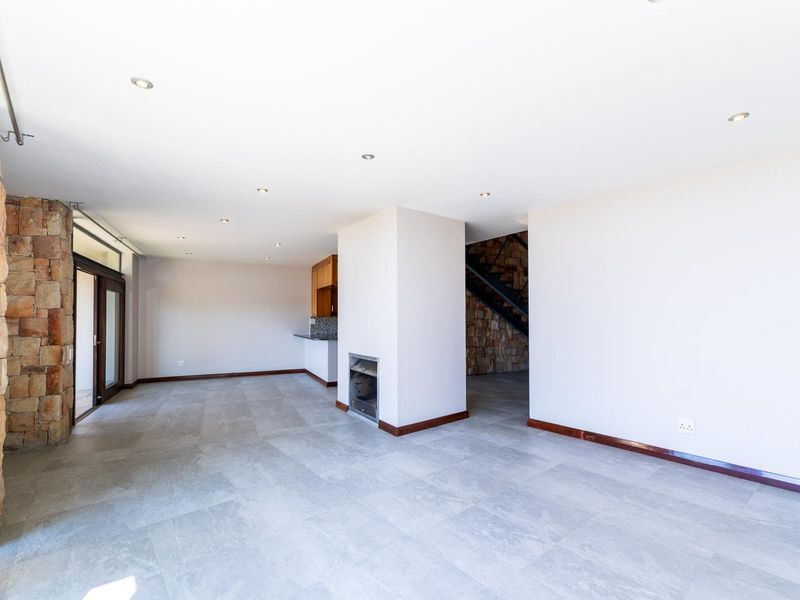 Spacious open-plan living area featuring stone cladding, a built-in fireplace, modern tiled flooring, and recessed lighting, offering a bright and versatile layout.