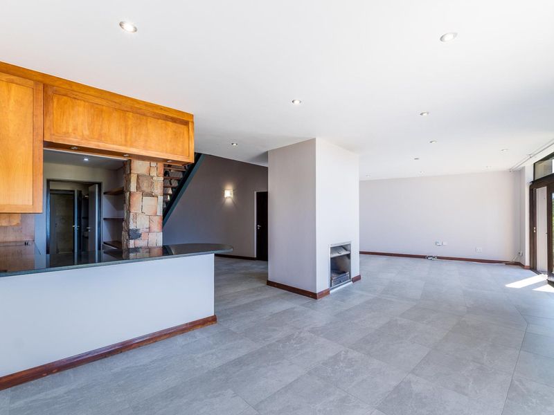 Spacious open-plan living area featuring a kitchen with granite countertops, a stone-clad fireplace, and large sliding doors leading to the exterior.