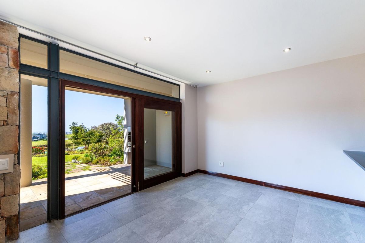 Bright and spacious living area featuring large sliding glass doors that open onto a patio, with modern tiled flooring and recessed lighting.