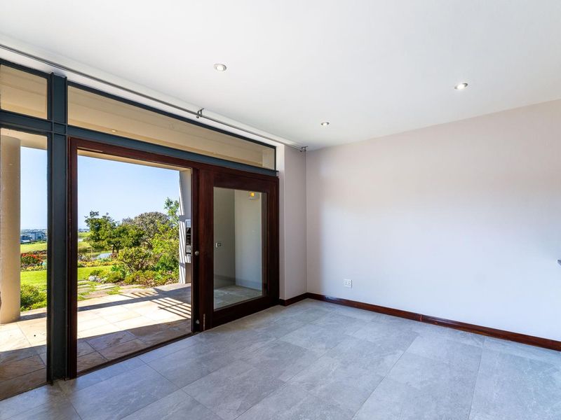 Bright and spacious living area featuring large sliding glass doors that open onto a patio, with modern tiled flooring and recessed lighting.