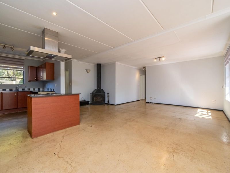 Spacious open-plan living area featuring a kitchen with island, extractor fan, and a central freestanding fireplace, finished with tiled flooring throughout.