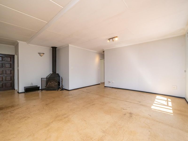 Spacious living area featuring a freestanding fireplace, tiled flooring, and neutral walls, offering a blank canvas for interior design.