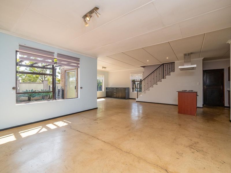 Spacious open-plan living area featuring polished concrete floors, a staircase with metal balustrade, and a built-in extractor fan.