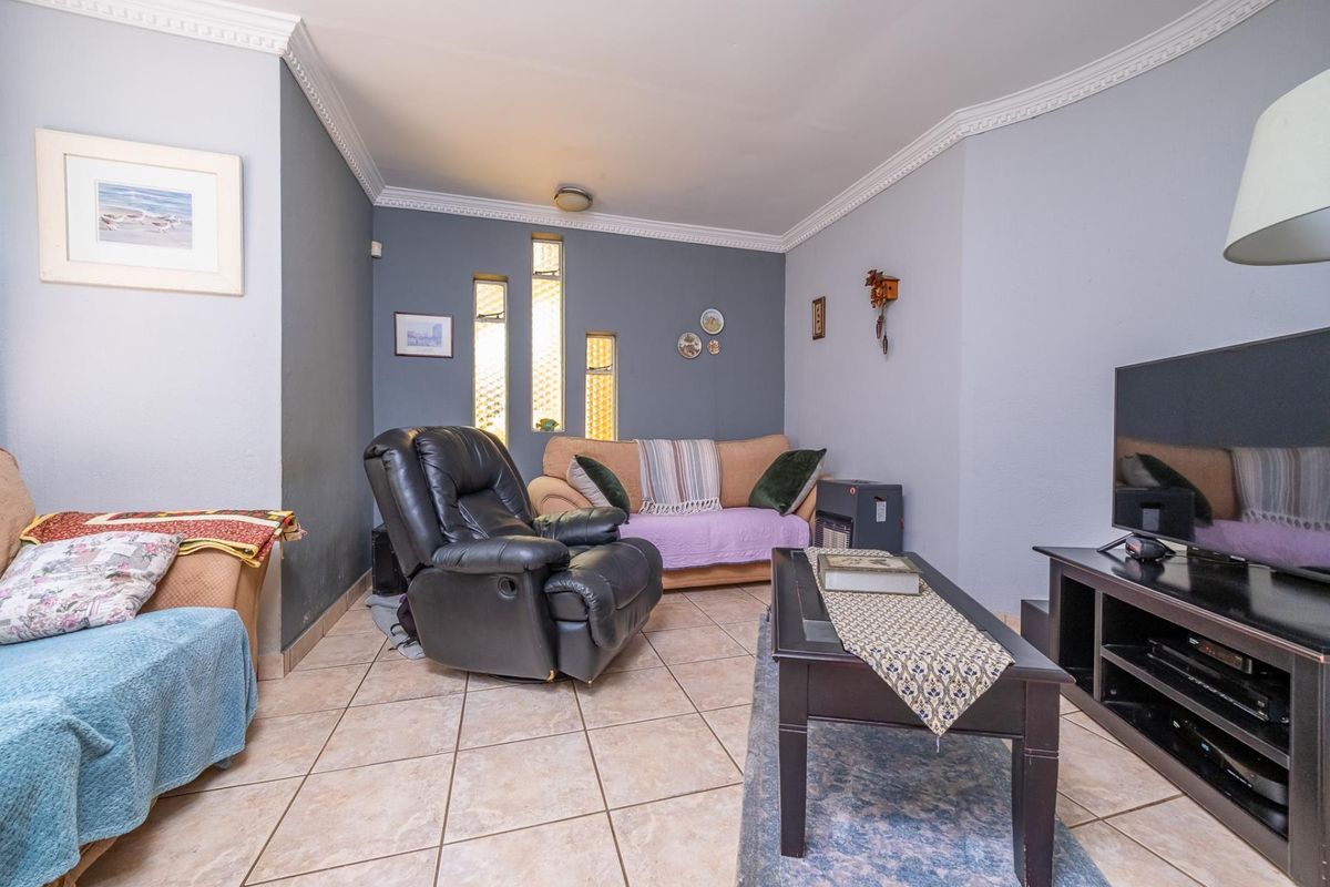 A cozy living room featuring tiled flooring, decorative crown molding, and unique vertical accent windows, providing a comfortable and functional living space.