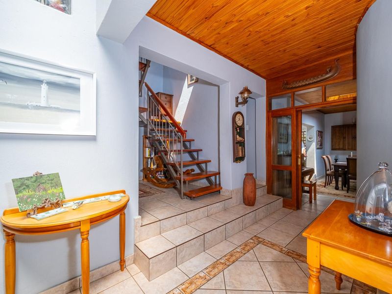 Welcoming entrance hall featuring a timber-clad ceiling, tiled flooring with decorative inlay, and a staircase leading to the upper level.