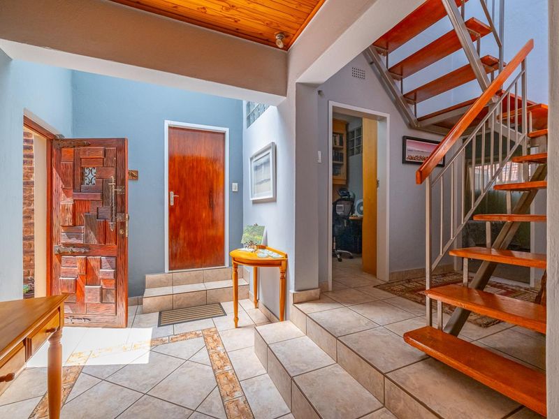 Welcoming entrance hall featuring a timber staircase, tiled flooring, and decorative timber ceiling paneling, providing access to multiple areas of the home.