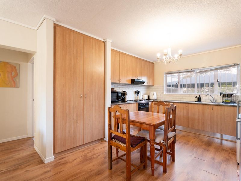 A functional kitchen featuring light wood cabinetry, subway tile backsplash, laminate flooring, and a built-in oven with an extractor fan.