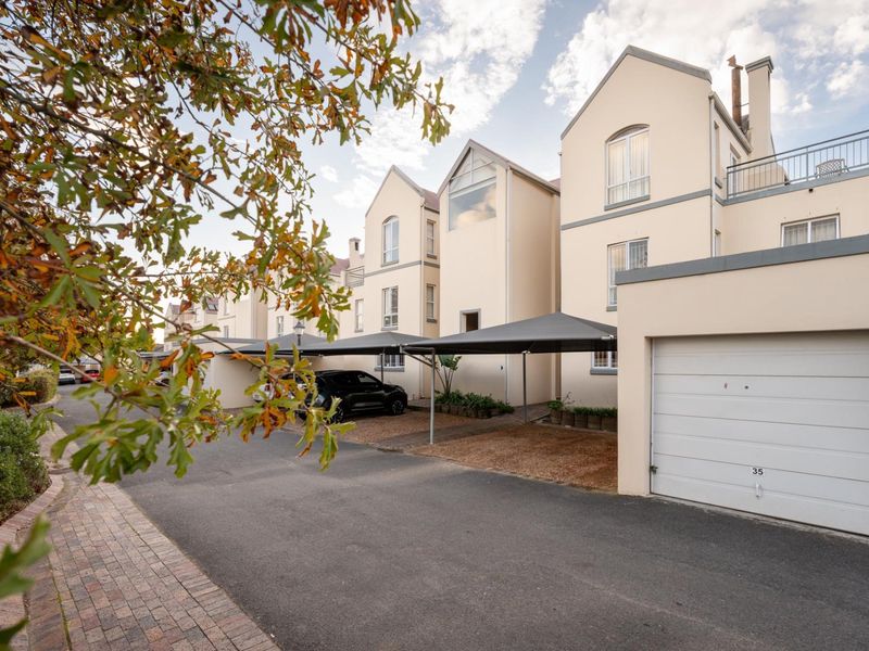 Front exterior view of the apartment complex featuring a paved driveway, covered carports, and a private garage.