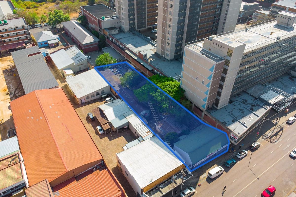 Aerial view of a commercial property site featuring multiple structures, metal roofing, and paved access areas within an urban environment.