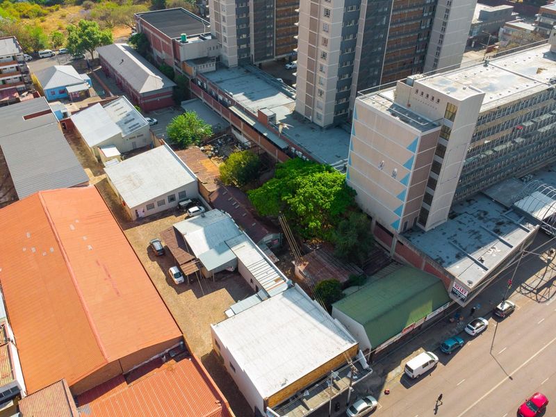 Aerial view of a commercial property complex featuring multiple buildings with corrugated metal roofing and paved access areas in an urban setting.
