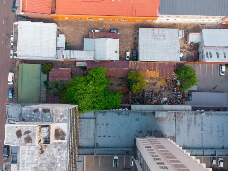 Aerial view of a commercial property complex featuring multiple buildings with metal roofing, parking areas, and a central courtyard space.