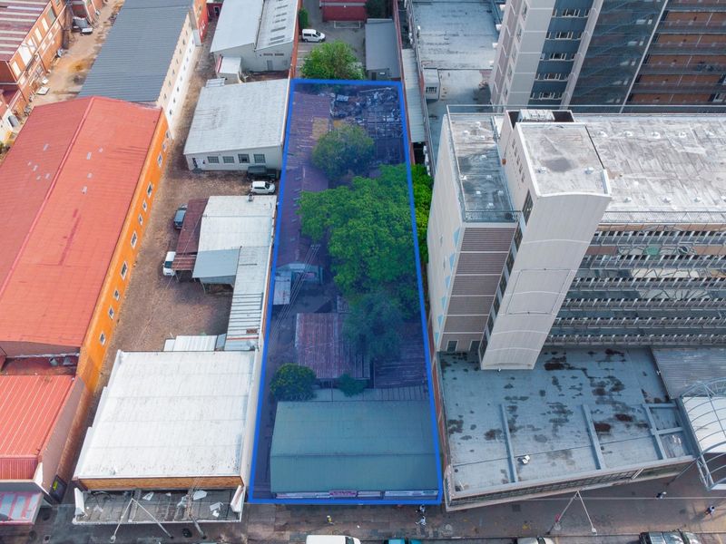 Aerial view of a commercial property plot featuring multiple structures, metal roofing, and a rear yard area in an urban setting.