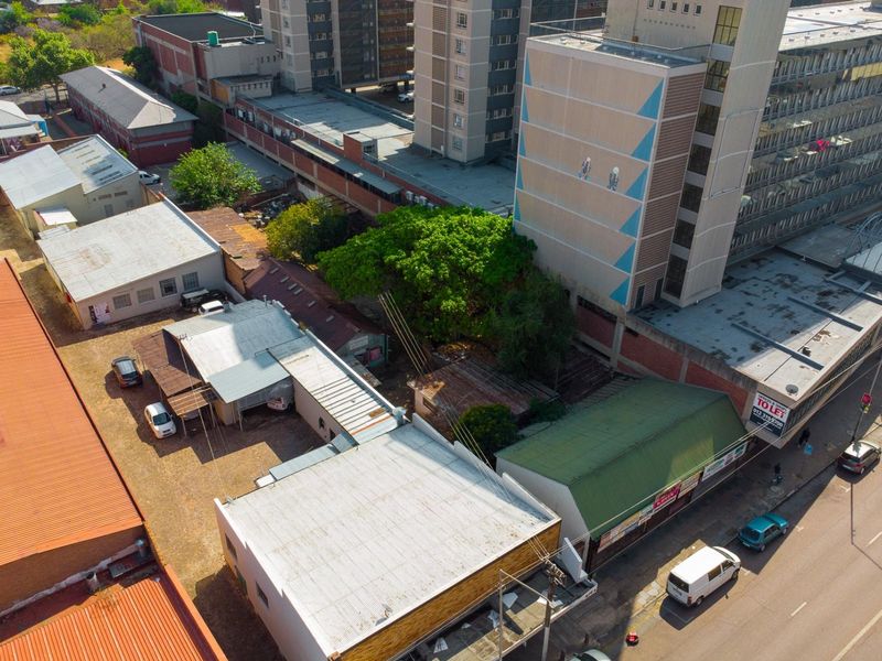 Aerial view of a commercial property complex featuring multiple buildings with corrugated metal roofing and an adjacent parking area.