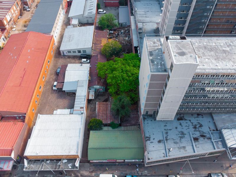 Aerial view of a commercial property complex featuring multiple buildings with corrugated metal roofs and an internal courtyard area with mature trees.