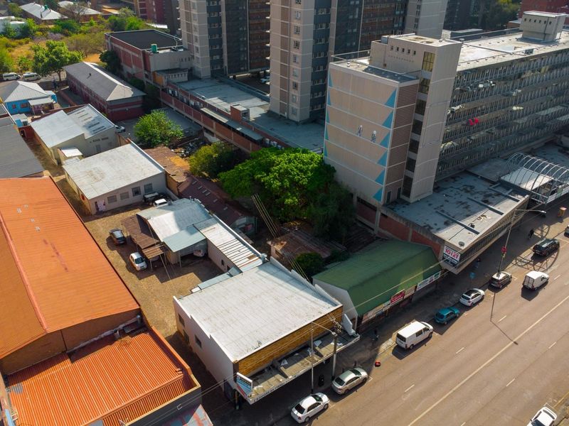 Aerial view of a commercial property complex featuring multiple buildings with corrugated metal roofing and street-level access in an urban environment.