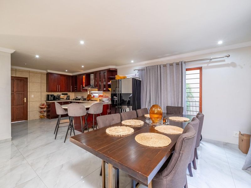 Spacious open-plan living area featuring a modern kitchen with dark wood cabinetry, a central island, and seamless flow to the dining space with tiled floors.