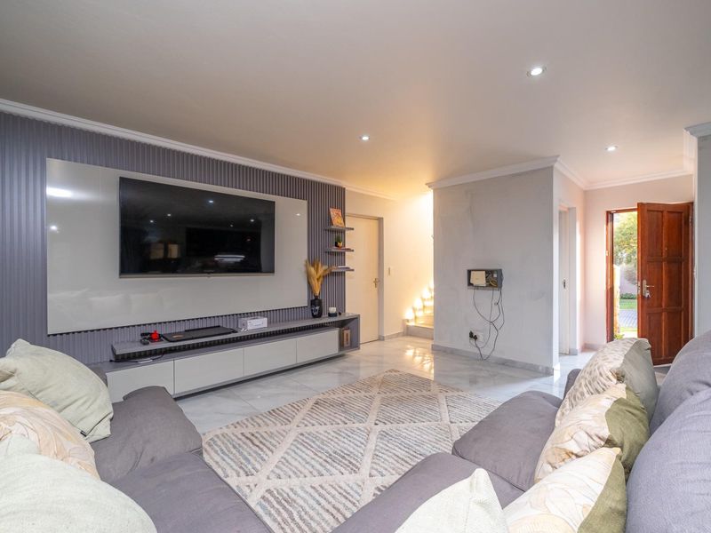 Modern living room featuring a sleek built-in media wall, tiled flooring, recessed lighting, and direct access to the exterior.