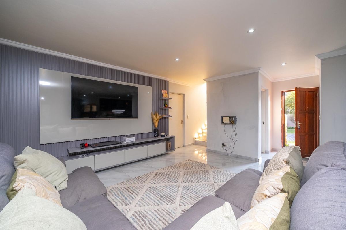 Modern living room featuring a sleek built-in media wall, tiled flooring, recessed lighting, and direct access to the exterior.
