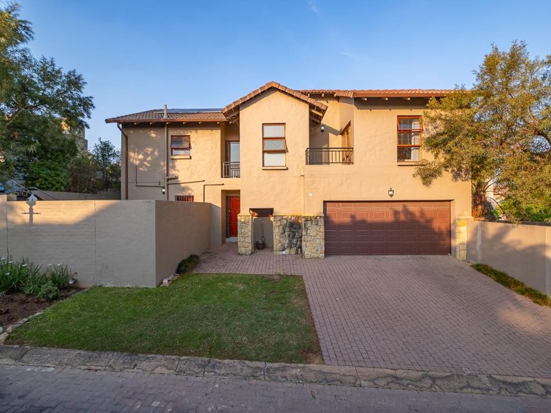 A well-maintained double-story residential property featuring a paved driveway, double garage, stone-clad entrance detail, and a balcony.
