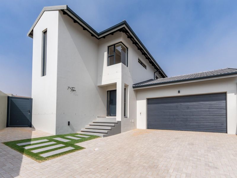 Modern double-storey residential home featuring a clean white facade, paved driveway, integrated double garage, and a welcoming stepped entrance.