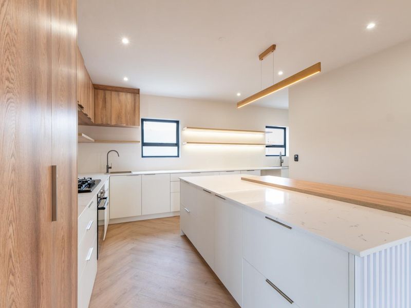 Modern, high-end kitchen featuring a large central island, stone countertops, herringbone flooring, and sleek built-in cabinetry with integrated lighting.