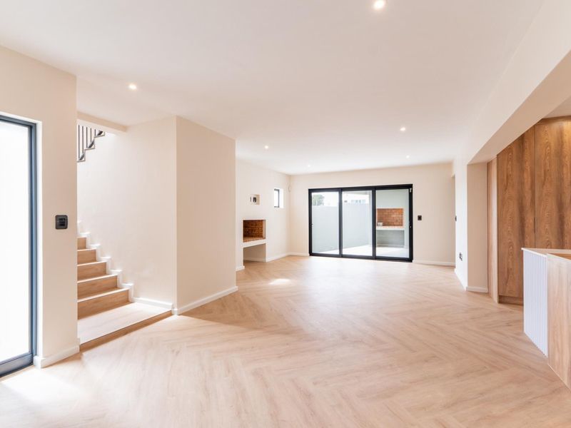 Spacious open-plan living area featuring modern herringbone flooring, recessed lighting, a built-in fireplace, and seamless access to the outdoor patio area.