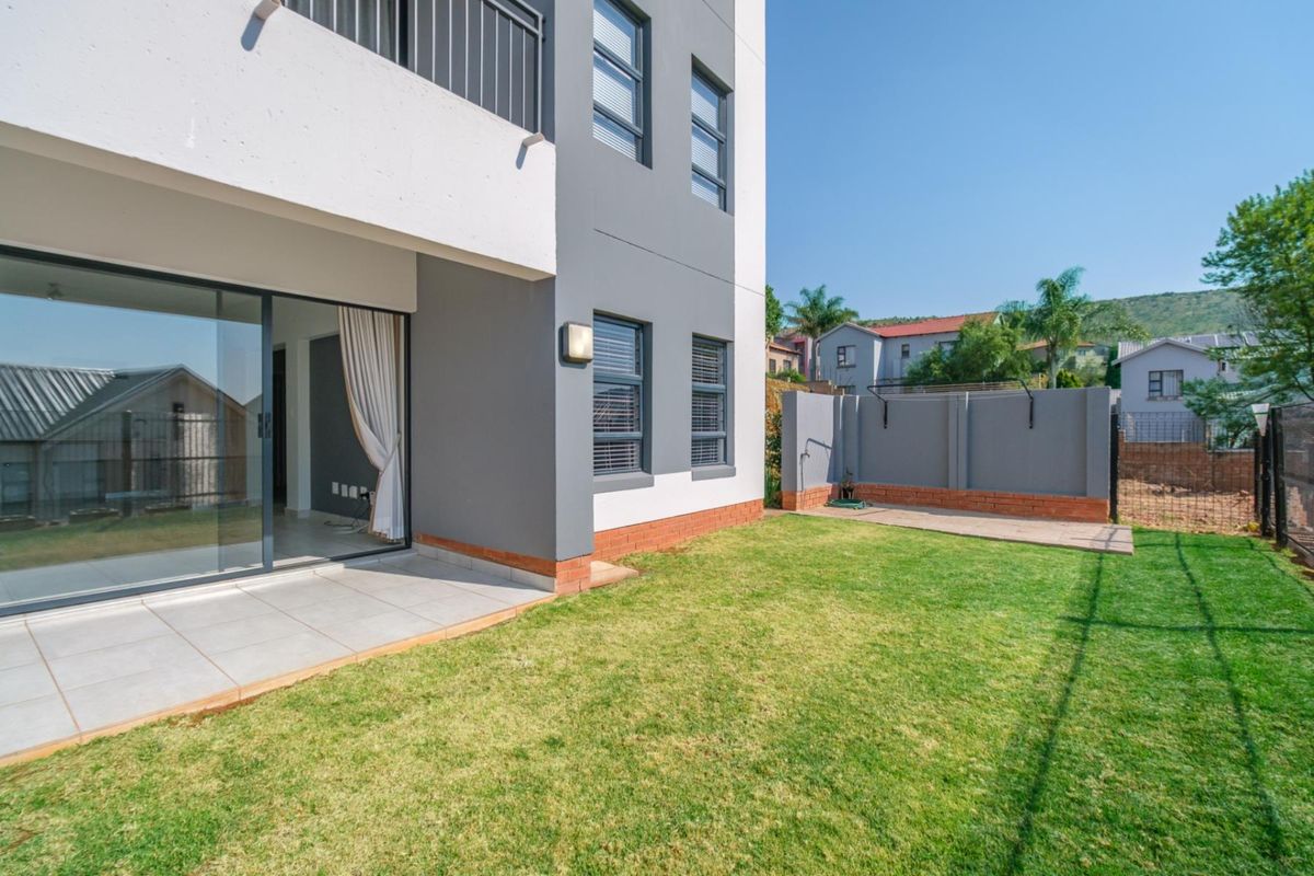 A private rear garden featuring a tiled patio area, sliding door access to the apartment, and a secure boundary wall.