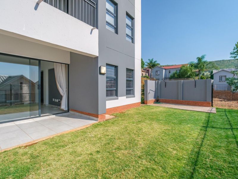 A private rear garden featuring a tiled patio area, sliding door access to the apartment, and a secure boundary wall.