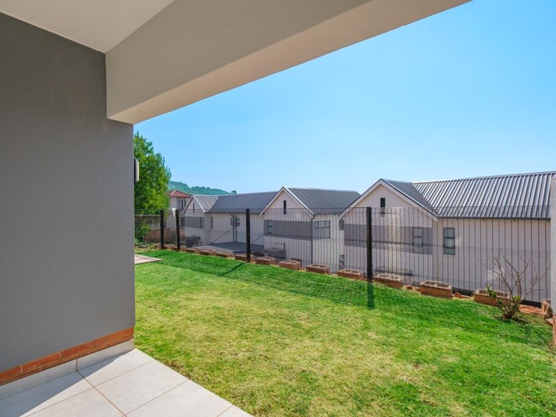 A covered patio area overlooking a private lawn and neighbouring residential properties with secure perimeter fencing.