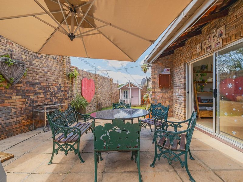A covered outdoor patio area featuring exposed brick walls, paved flooring, and direct access to the interior through a sliding glass door.