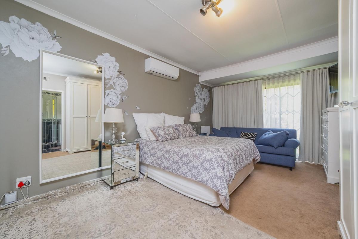 Spacious bedroom featuring carpeted flooring, an integrated air conditioning unit, and a built-in wardrobe with direct access to an outdoor area.