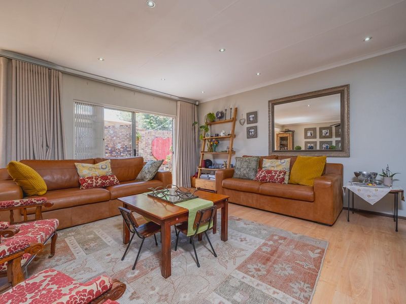 A well-maintained living room featuring laminate flooring, recessed downlighting, and a large sliding glass door providing access to the outdoor area.