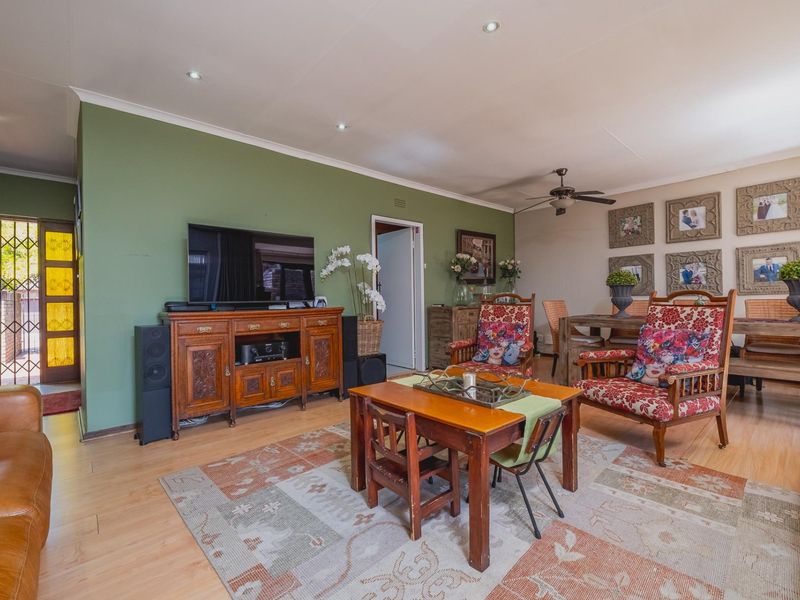 Spacious open-plan living and dining area featuring laminate flooring, recessed downlighting, and a ceiling fan, with direct access to an exterior security gate.