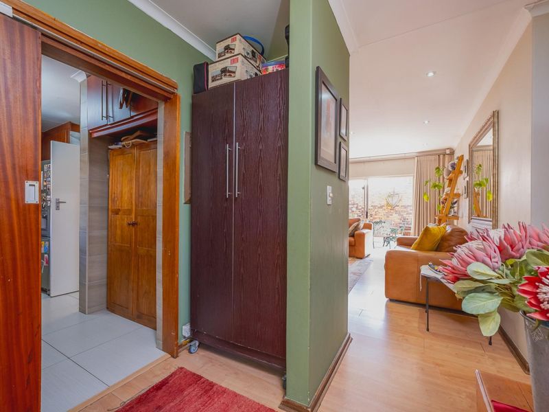 A functional hallway connecting the kitchen and living areas, featuring laminate and tiled flooring with built-in storage cabinetry.