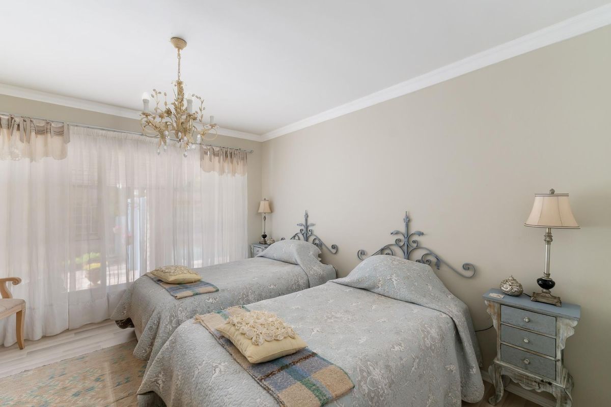 A well-maintained bedroom featuring crown molding, a decorative chandelier, and a sliding glass door providing natural light.