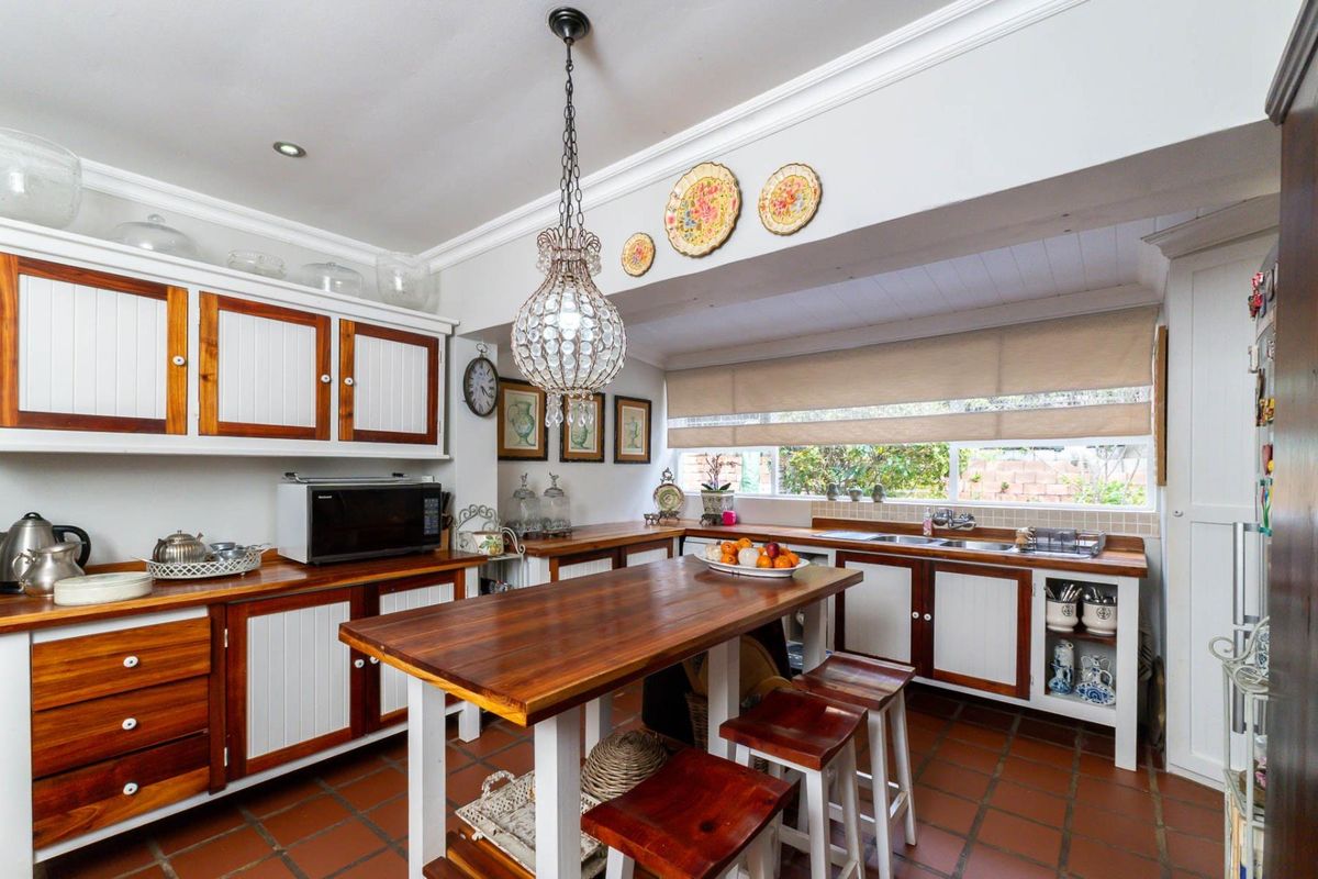 A charming kitchen featuring warm wooden cabinetry, matching timber countertops, terracotta flooring, and a central island, creating a cozy and functional culinary space.
