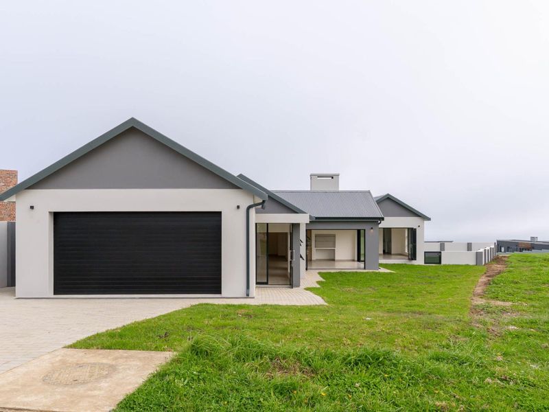 Rear view of a modern single-story home featuring a double garage, covered patio area, and a spacious lawn.