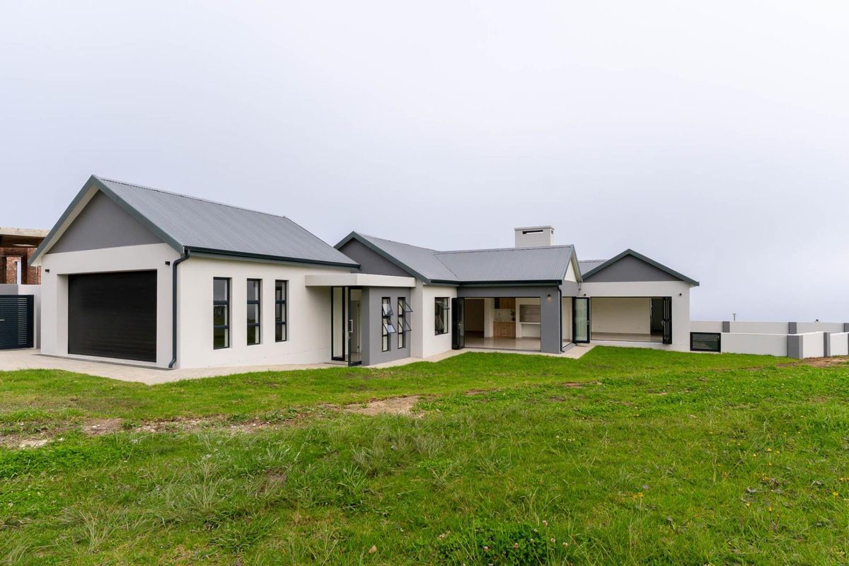 Rear view of a modern single-story house featuring a corrugated metal roof, integrated garage, and a covered patio area with bi-fold doors.