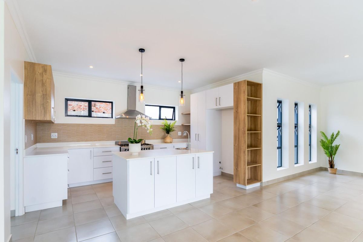 Modern kitchen featuring white cabinetry, a central island, stainless steel stove, extractor fan, tiled backsplash, and neutral floor tiles in an open-plan layout.