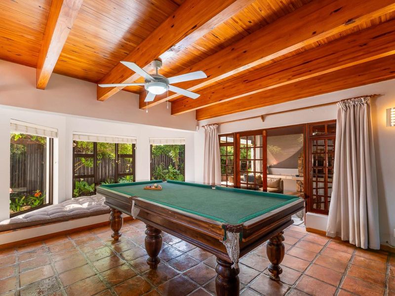 Spacious living area featuring exposed timber ceiling beams, terracotta floor tiles, a built-in window seat, and direct access to the outdoor patio.