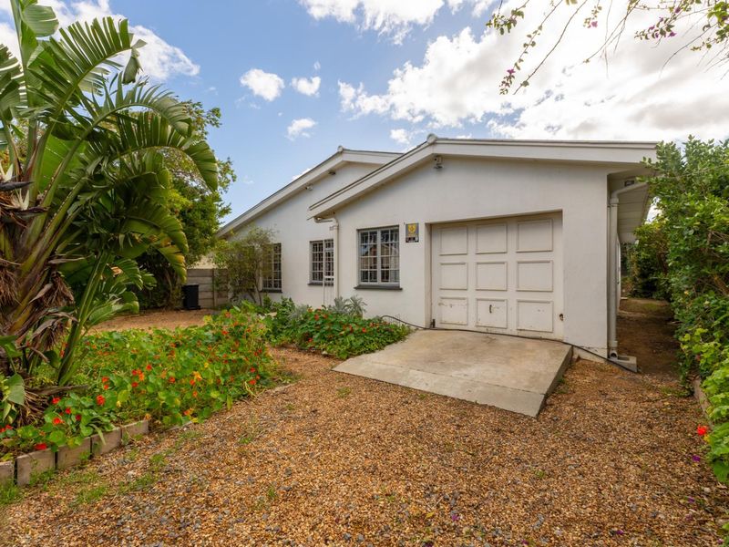 Front exterior view of the property featuring a single garage, gravel driveway, and established garden beds.