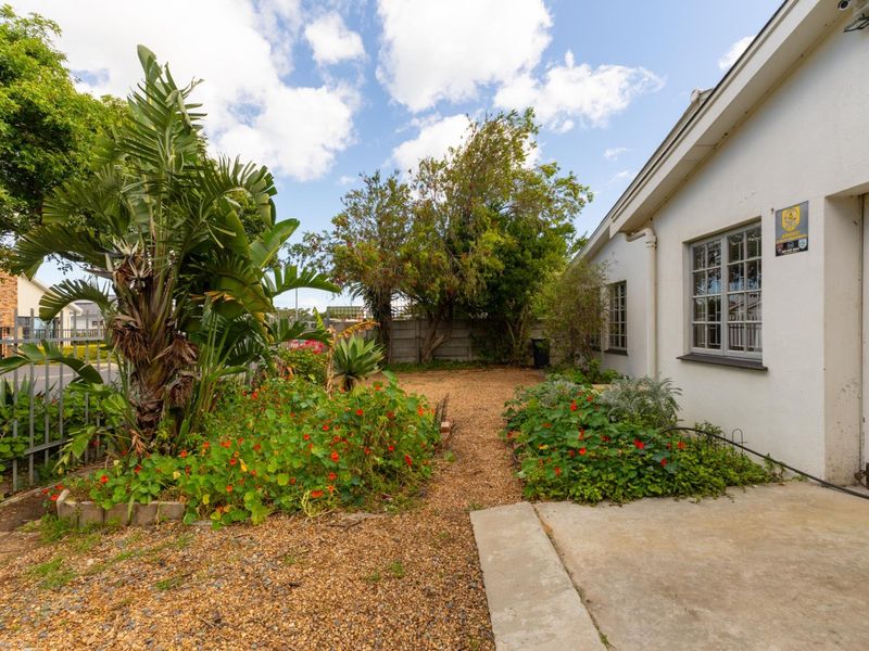 A low-maintenance garden area featuring a gravel pathway, established greenery, and a concrete patio adjacent to the side of the house.