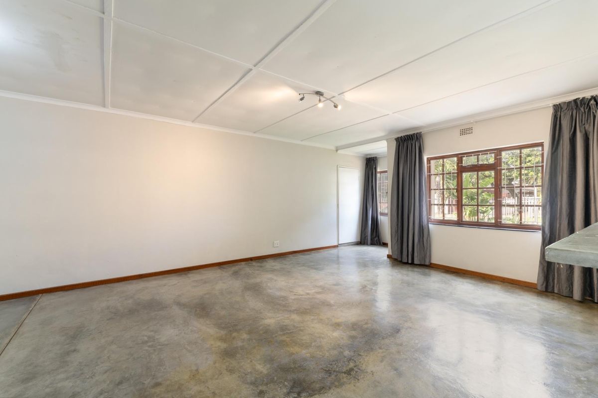 Spacious living area featuring polished concrete flooring, timber-framed windows, and a neutral color palette, offering a blank canvas for personalization.