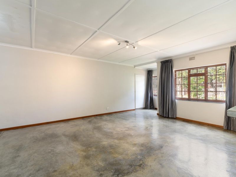 Spacious living area featuring polished concrete flooring, timber-framed windows, and a neutral color palette, offering a blank canvas for personalization.