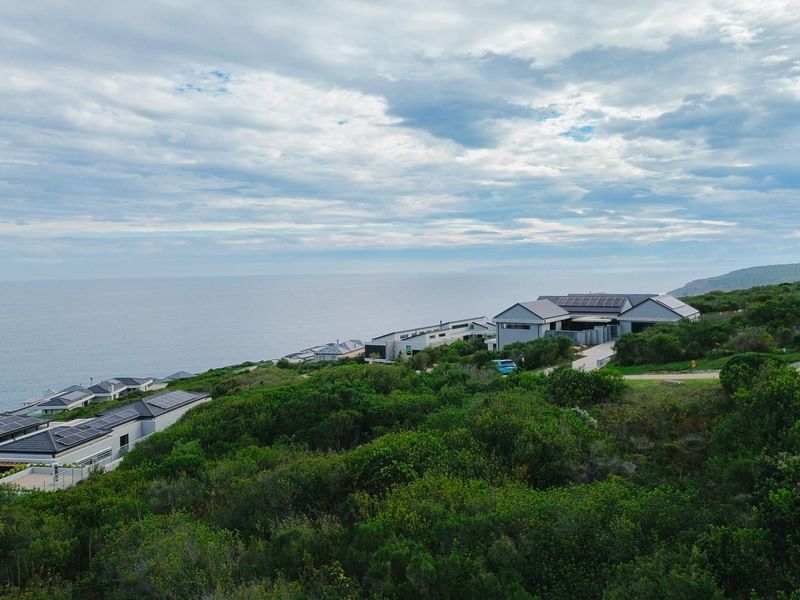 An aerial view of a coastal residential estate surrounded by natural vegetation, showcasing the property's location and surrounding landscape.