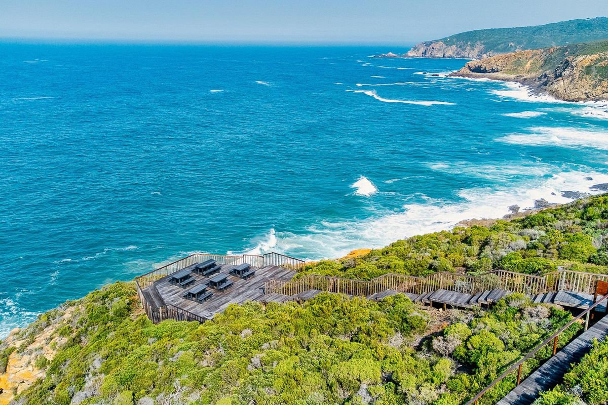 Elevated coastal view featuring a timber viewing deck and staircase overlooking the ocean and rugged coastline.