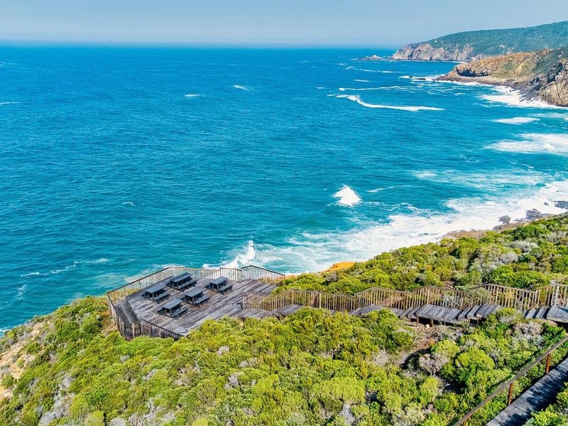 Elevated coastal view featuring a timber viewing deck and staircase overlooking the ocean and rugged coastline.
