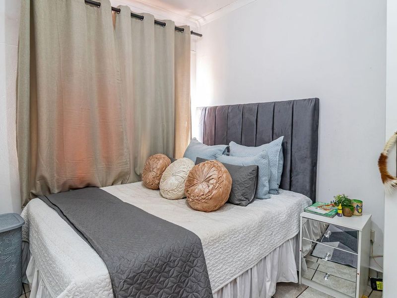 A cozy bedroom featuring neutral wall finishes and window treatments, providing a comfortable and functional sleeping space.