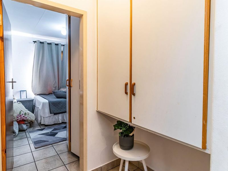 A functional hallway featuring built-in storage cabinetry and tiled flooring, providing access to an adjacent bedroom.