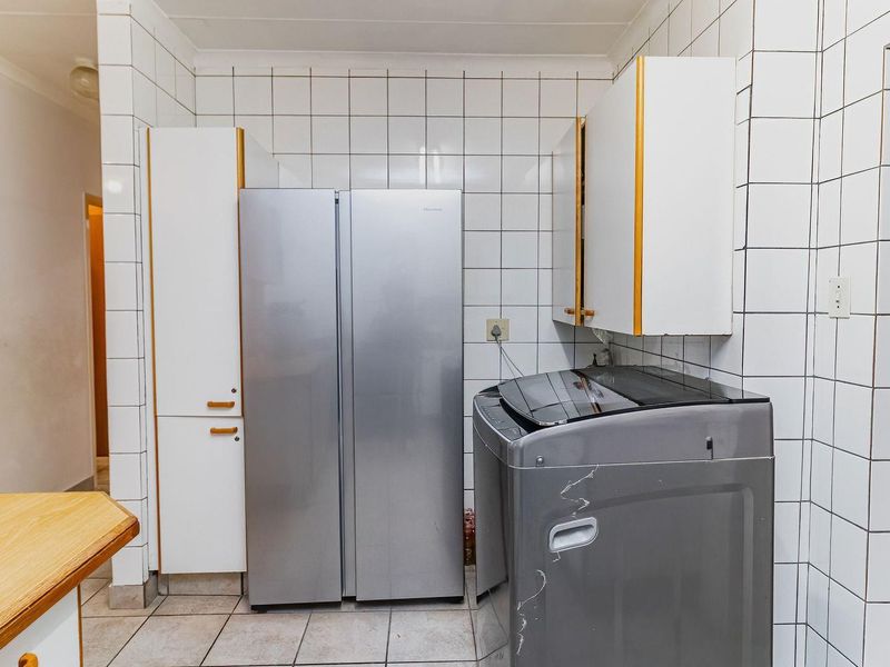 A functional laundry area featuring tiled walls, tiled flooring, and built-in cabinetry providing storage space for utility needs.